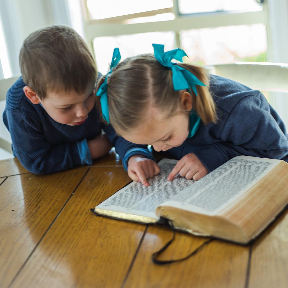Two young children reading the Bible