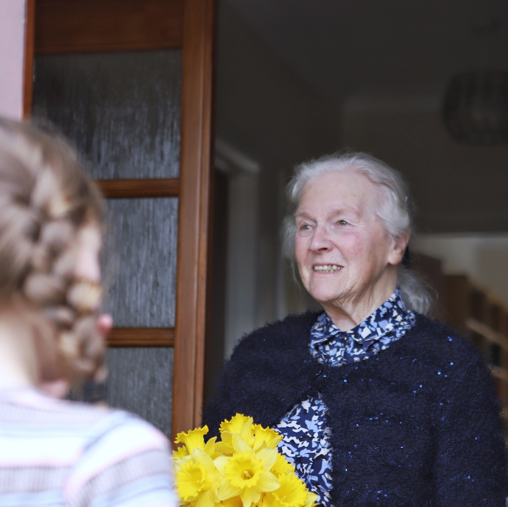 Young girl delivering flowers to elderly neighbour