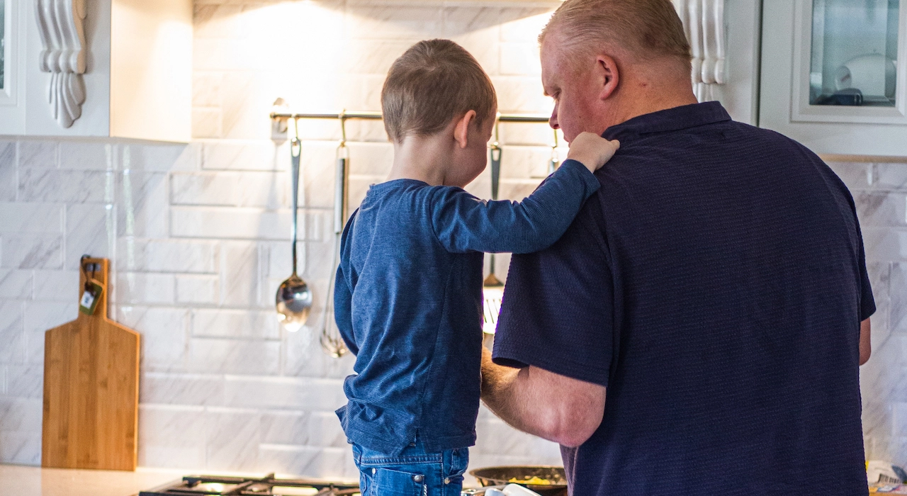 Young boy cooking with father